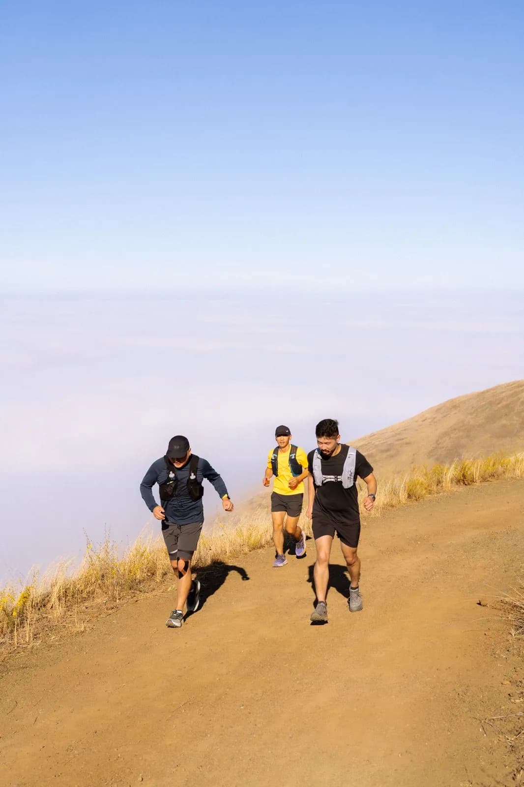Three runners climbing above the cloud layer
